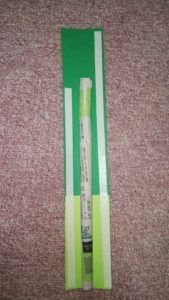 切られた黄緑と緑の画用紙に両面テープを貼り、新聞紙の棒を合わせたところ