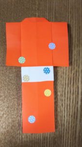 オレンジの折り紙で作った紙衣にシールが貼られている