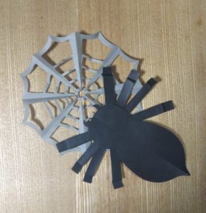 灰色の折り紙で作ったクモの巣と黒い折り紙で作ったクモ