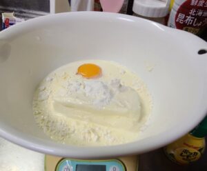 常温のクリームチーズに砂糖、小麦粉、全卵の入った白いボウル