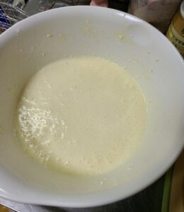 常温のクリームチーズに砂糖、小麦粉、全卵を入れてハンドミキサーで混ぜたものが入った白いボウル
