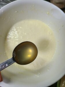 常温のクリームチーズに砂糖、小麦粉、全卵を入れてハンドミキサーで混ぜたものが入った白いボウルにレモン汁を足すところ